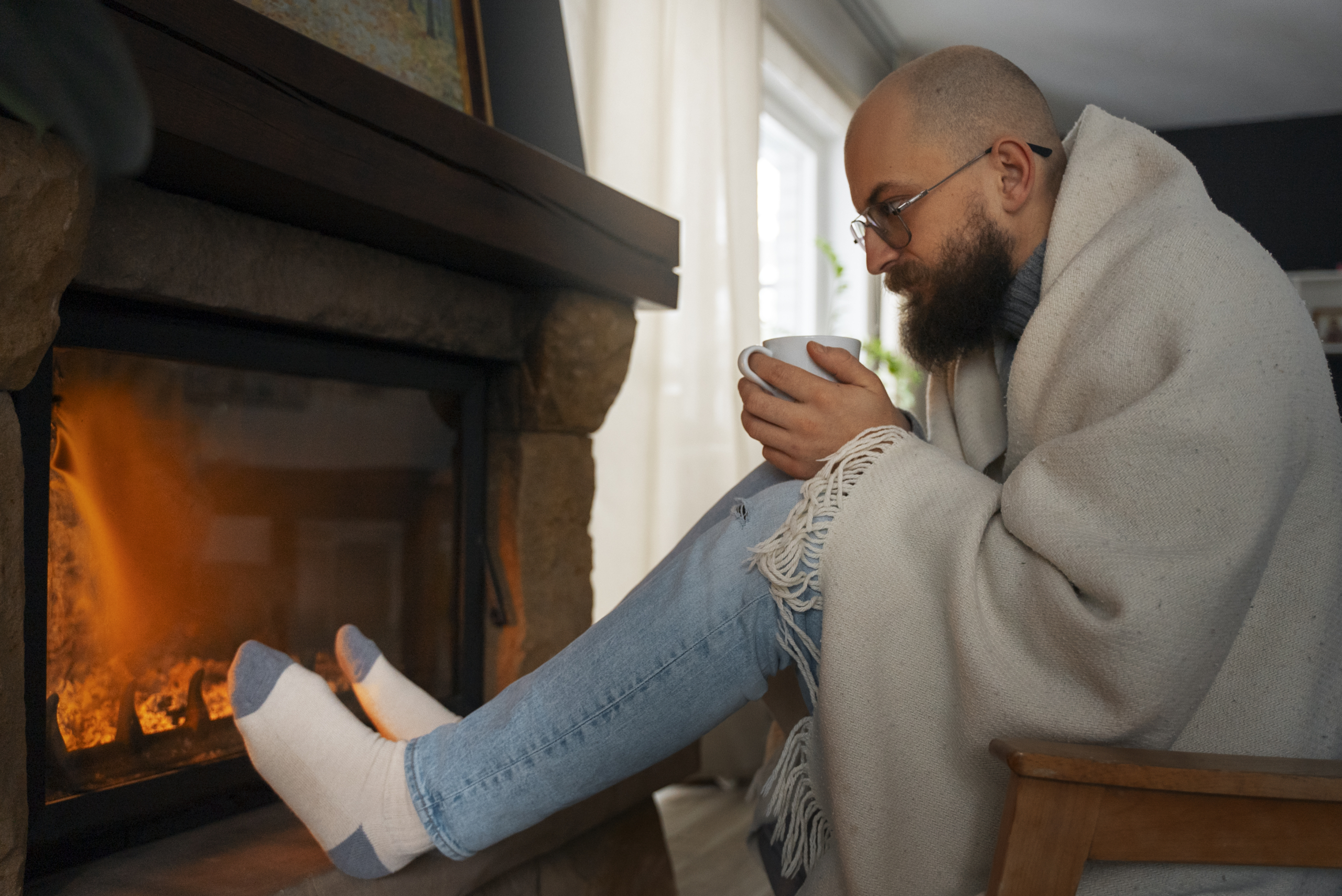 Man holding coffee by a gas fireplace